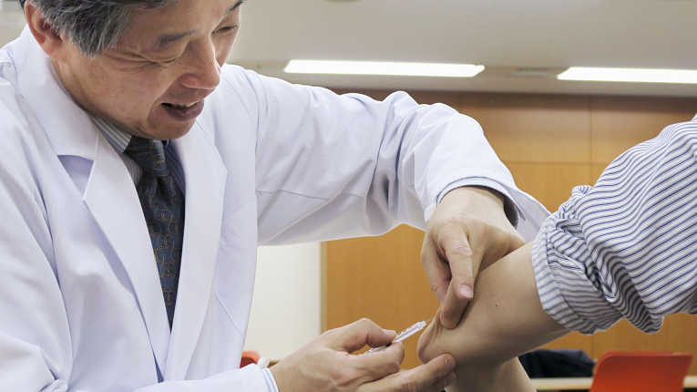 Medico japonês aplicando injeção