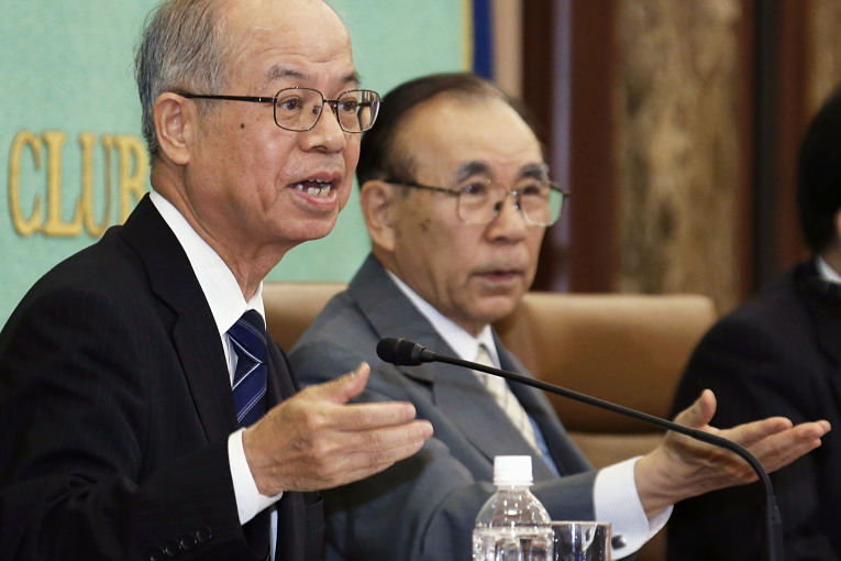 Professor de política pela Kokushikan University Akira Momochi discursando ao microfone do lado esquerdo da imagem