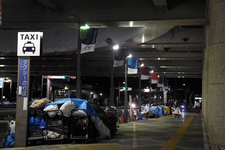 Pessoas em situação de rua em Tokyo dormem embaixo de banners dos Jogos Olímpico