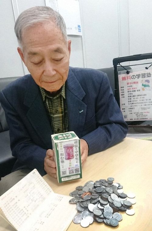 Mitsuhiro Yoshimoto segura caixa de doações e as moedas coletadas para financiar a organização sem fim lucrativos que coordena, a Nagamu da cidade de Kitakyushu