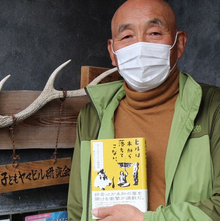 Professor Dairyo Higuchi, 75, coordenador do grupo Kodomo Yamabiru Kenkyu-kai segurando um exemplar do livro Hiru wa Ki kara Ochite Konai (Sanguessugas não caem das árvores)