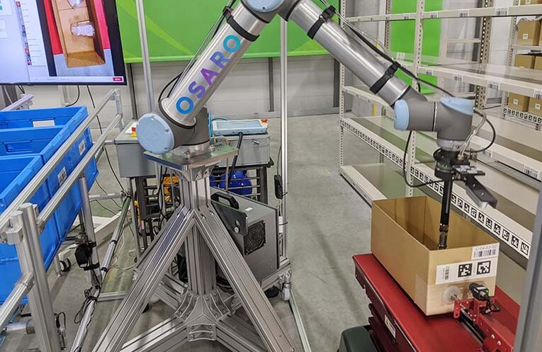 Robô coletor (esquerda) seleciona um produto e o deposita em uma embalagem no robô móvel autônomo (direita)