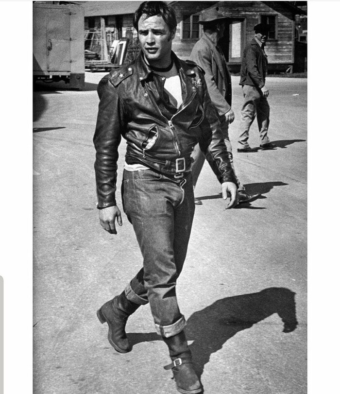 Marlon Brando usando jeans com barra dobrada, camiseta branca e jaqueta de couro preta