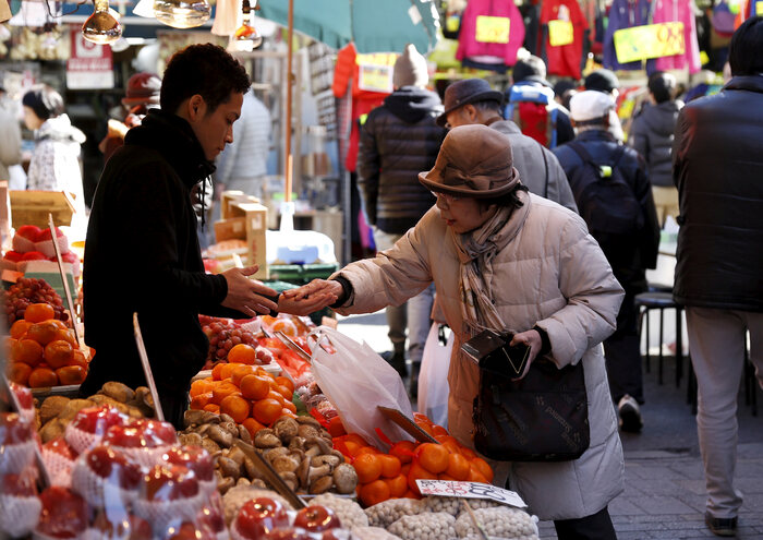 Mulher compra frutas em feira no Japão
