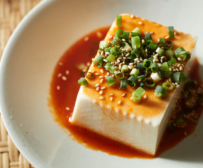 Bloco de tofu seda é servido com molho shoyu e toppings no estilo japonês