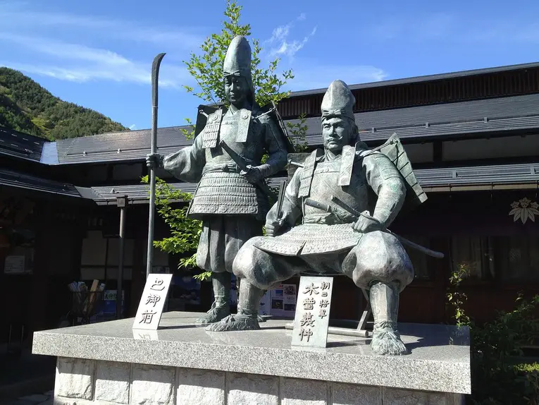 Estátua de Tomoe Gozen junto a seu amante Kiso no Yoshinaka no templo Tokuon-ji na cidade de Kiso, província de Nagano. Em muitas expressões artísticas, Tomoe Gozen é representada com uma naginata, uma típica arma utilizada pelas guerreiras Onna-musha, porém, Tomoe era especializada em espada longa e arco e flechas
