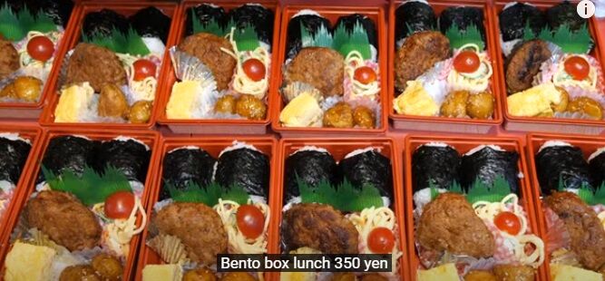 Bento de onigiri, hamburguer, salada, tamagoyaki
